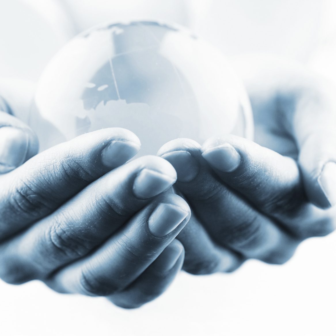 Hands gently cradling a clear glass sphere, conveying a sense of care and protection.